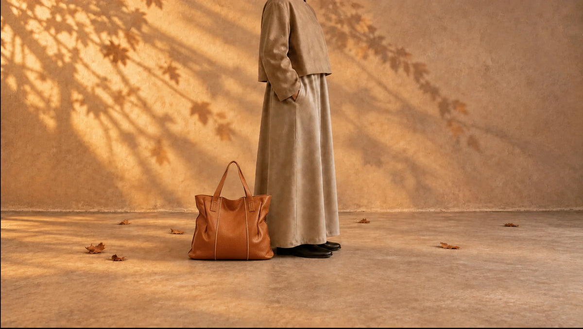 Personne en tenue beige près d’un grand sac cabas en cuir marron