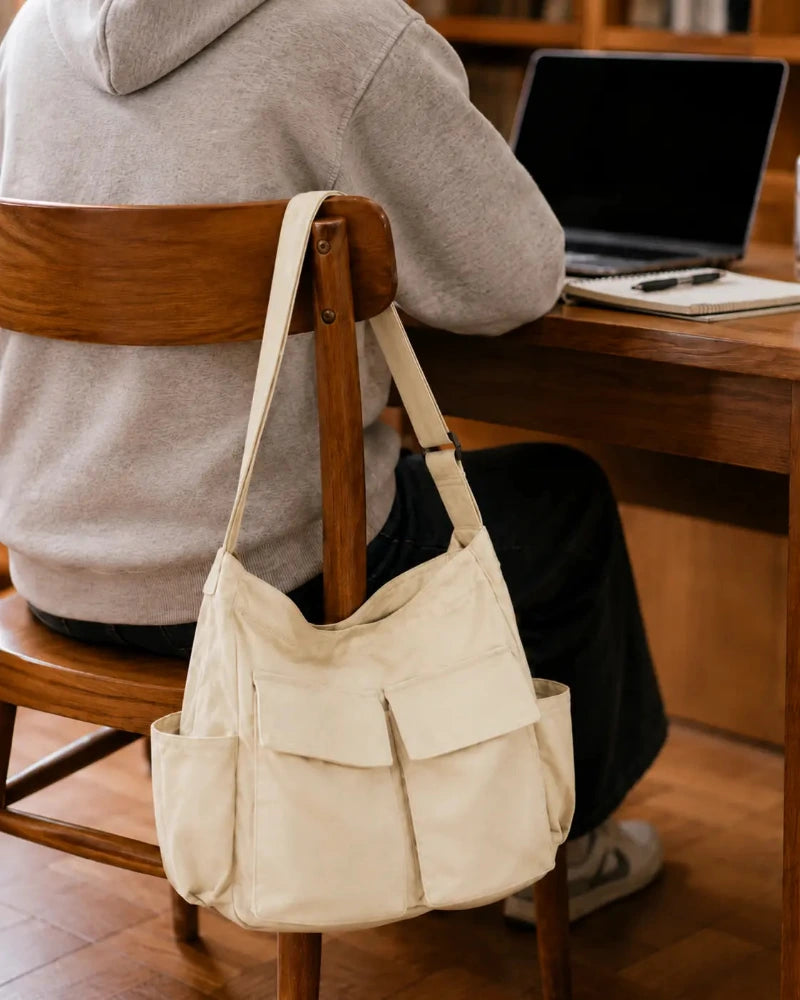 Sac cabas bandouliere blanc accroché à une chaise de bibliothèque 