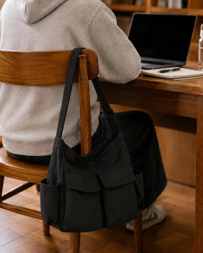 Sac cabas bandouliere noir accroché à une chaise de bibliothèque 
