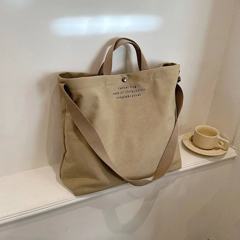 Sac cabas bandoulière en toile beige — posé sur meuble