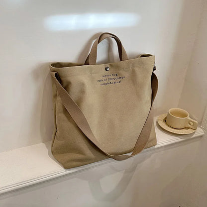 Sac cabas bandoulière en toile beige — posé sur meuble