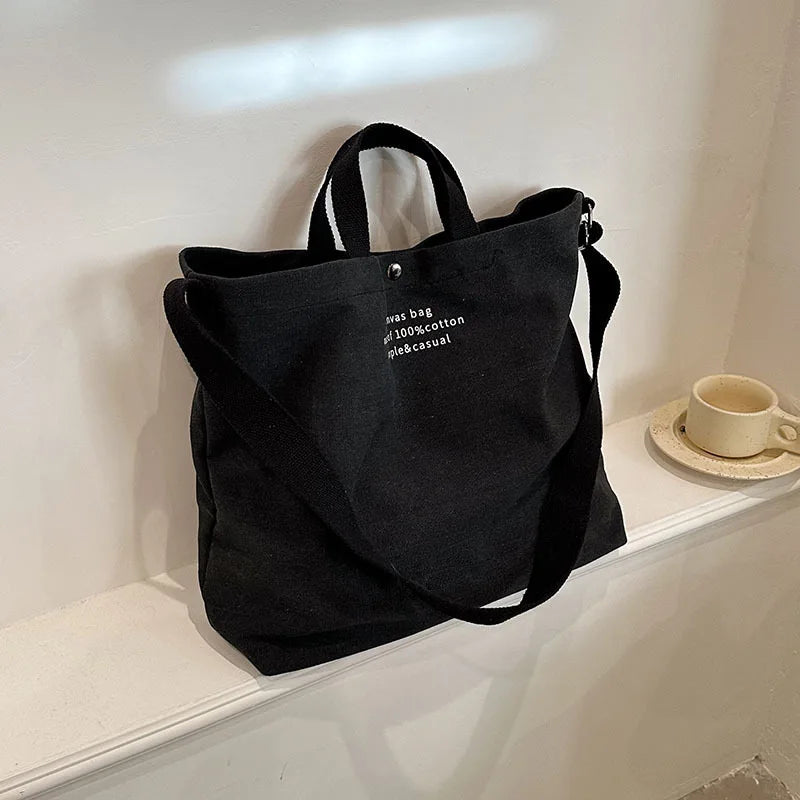 Sac cabas bandoulière en toile noir — posé sur meuble