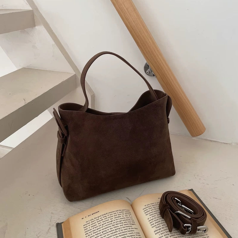 Sac cabas daim compact femme marron posé près d’un livre ouvert