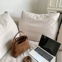 Sac cabas daim compact femme marron posé près d’un ordinateur