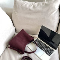 Sac cabas daim compact femme rouge vu de côté près d’un ordinateur