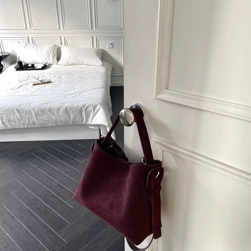 Sac cabas daim compact femme rouge suspendu à une porte