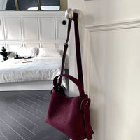 Sac cabas daim compact femme rouge avec bandoulière suspendu à une porte