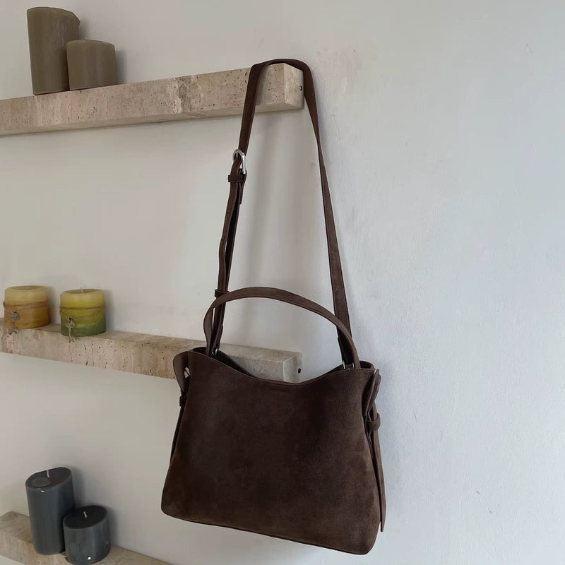 Sac cabas daim compact femme café suspendu devant des étagères